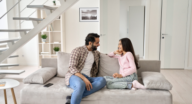 Image of a father and a daughter sitting on a couch, talking