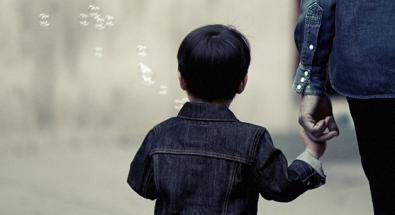 Image of a young child holding a hand and blowing bubbles
